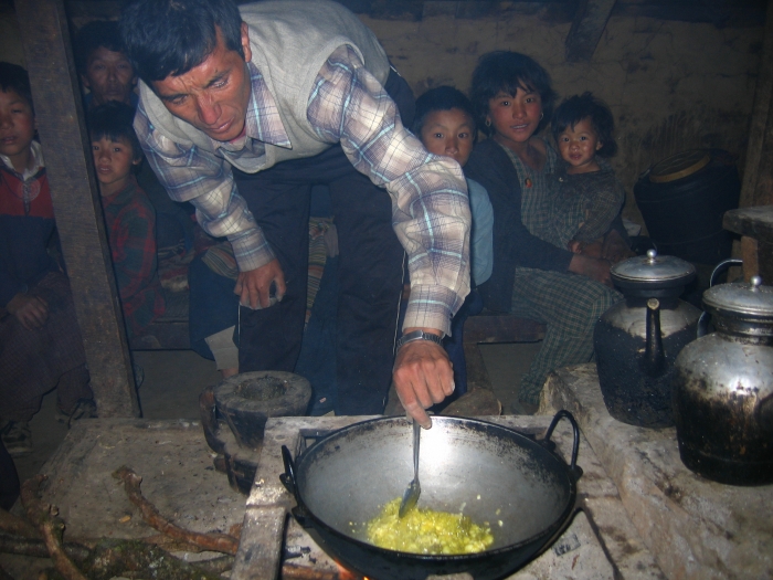 앙 다와 셰르파가 빠뿌레의 집에서 피케쪽으로 상당히 올라간 곳에 있는 농막에서 닭을 요리하기 위해 마늘을 기름에 볶고 있다. 뒤에 보이는 어린이들은 앙 다와의 자녀들과 이웃 사람들.